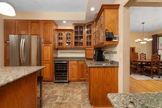 kitchen featuring beverage cooler, sink, decorative light fixtures, a chandelier, and stainless steel refrigerator