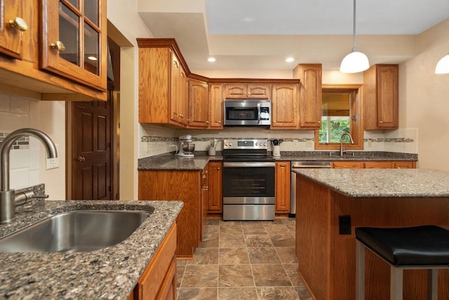 kitchen with pendant lighting, sink, stainless steel appliances, and tasteful backsplash