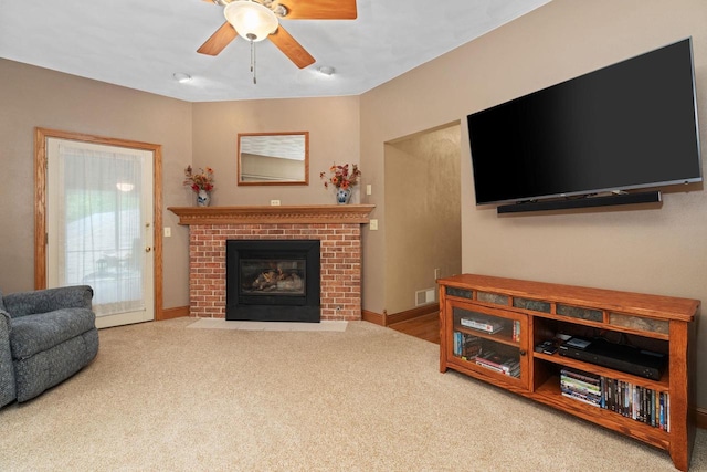 living room with ceiling fan, carpet floors, and a fireplace