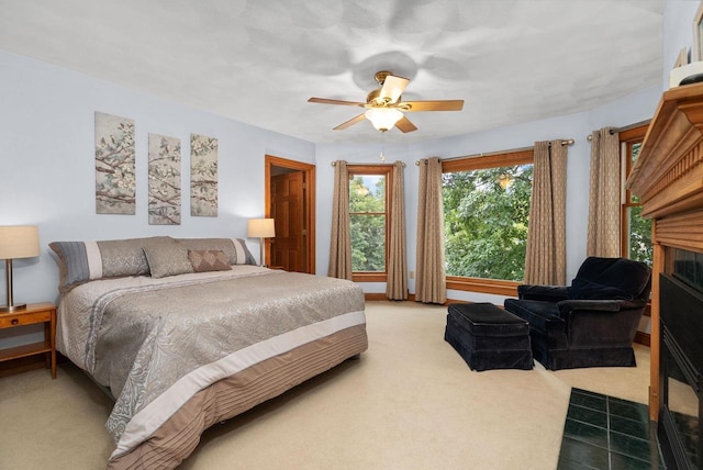 bedroom featuring carpet, ceiling fan, and a fireplace