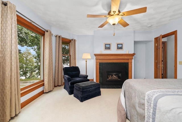 carpeted bedroom featuring ceiling fan and a tile fireplace