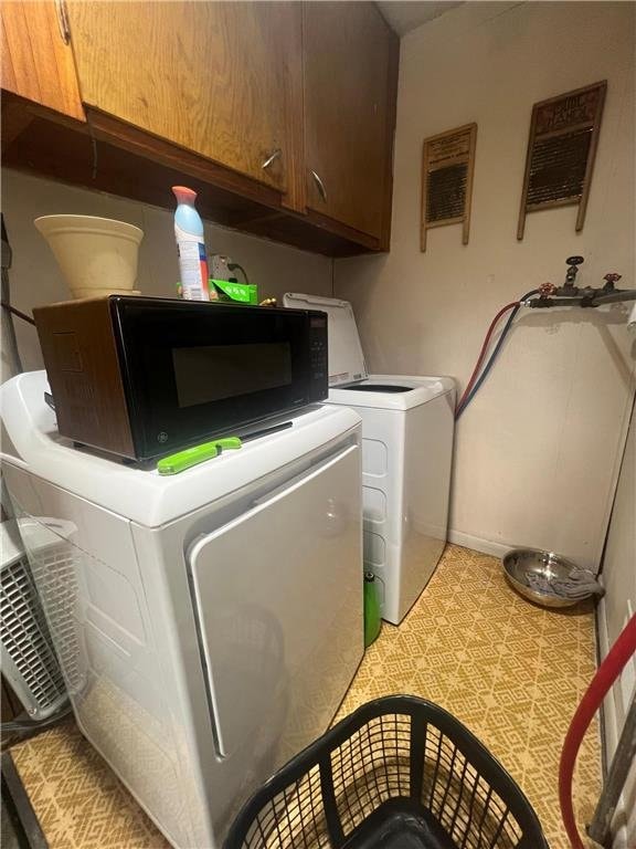 laundry room with washing machine and clothes dryer and cabinets