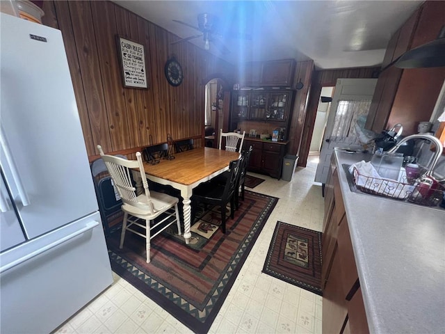 dining room featuring ceiling fan, sink, and wooden walls