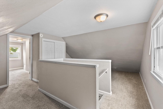 corridor with vaulted ceiling and light colored carpet