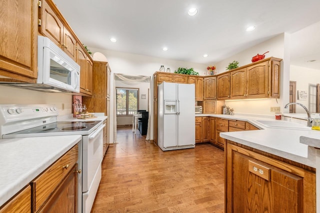 kitchen featuring light wood finished floors, light countertops, recessed lighting, white appliances, and a sink