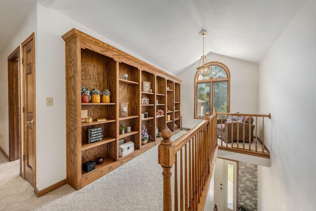 hallway featuring lofted ceiling, carpet flooring, an upstairs landing, and baseboards