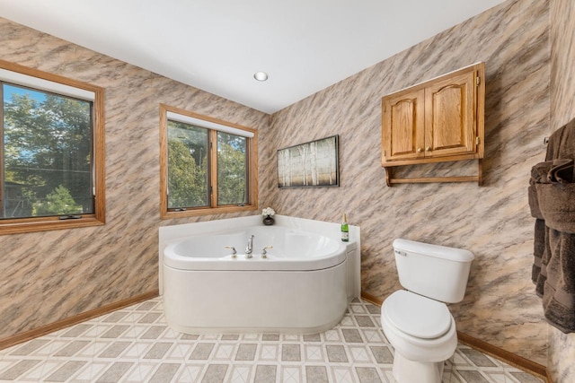 full bathroom featuring toilet, baseboards, and a garden tub