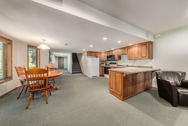 kitchen featuring electric range, freestanding refrigerator, a peninsula, black microwave, and light colored carpet