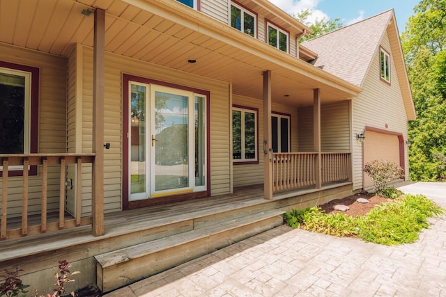 doorway to property featuring driveway and a shingled roof