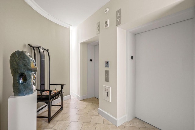 hallway with baseboards, elevator, light tile patterned flooring, and crown molding