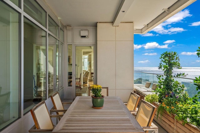 balcony featuring outdoor dining area and a water view