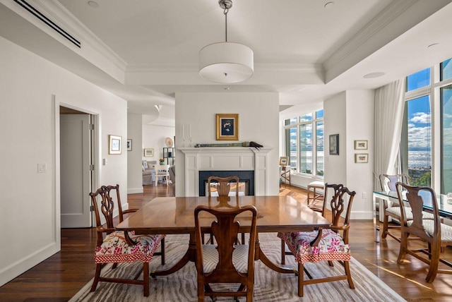 dining space featuring visible vents, crown molding, a tray ceiling, a fireplace, and wood finished floors