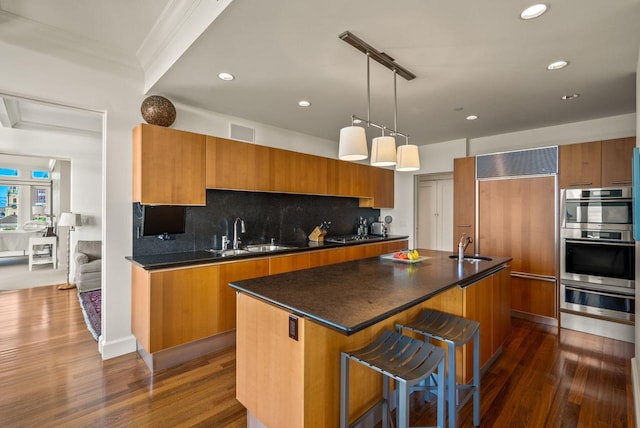 kitchen with brown cabinets, paneled fridge, modern cabinets, a warming drawer, and a sink