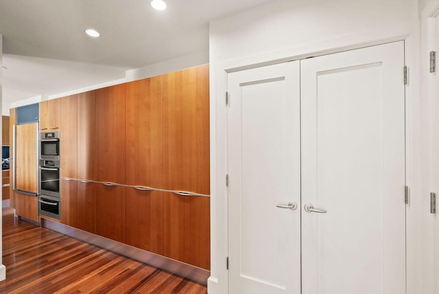 interior space with dark wood-style floors, recessed lighting, double oven, modern cabinets, and brown cabinets