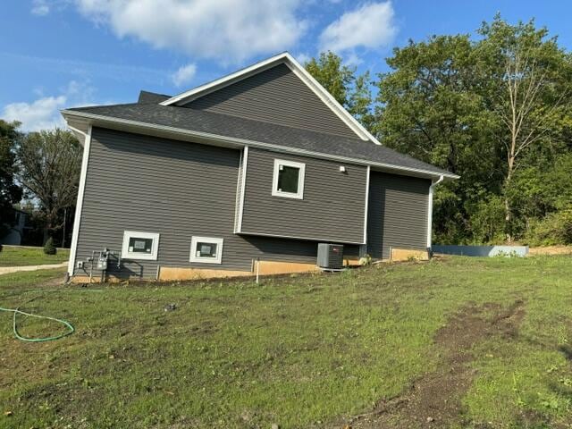 view of side of home featuring central AC unit and a yard