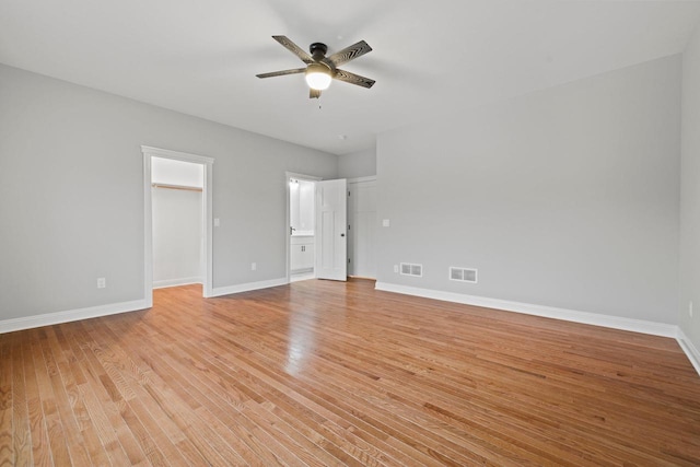 unfurnished bedroom with ceiling fan, light hardwood / wood-style flooring, a walk in closet, and a closet