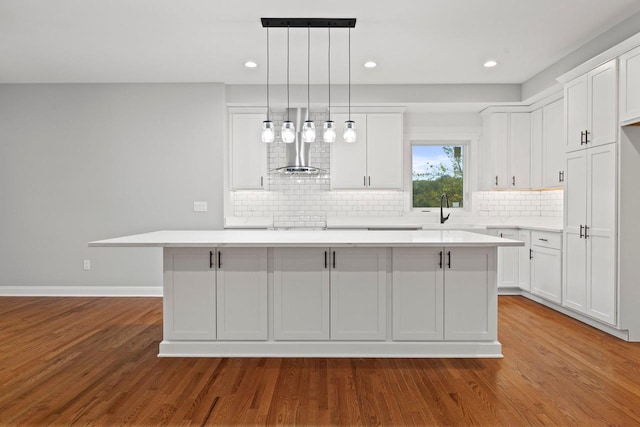 kitchen featuring decorative light fixtures, light hardwood / wood-style floors, white cabinetry, and a kitchen island