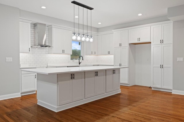 kitchen with wall chimney exhaust hood, a center island, and white cabinets