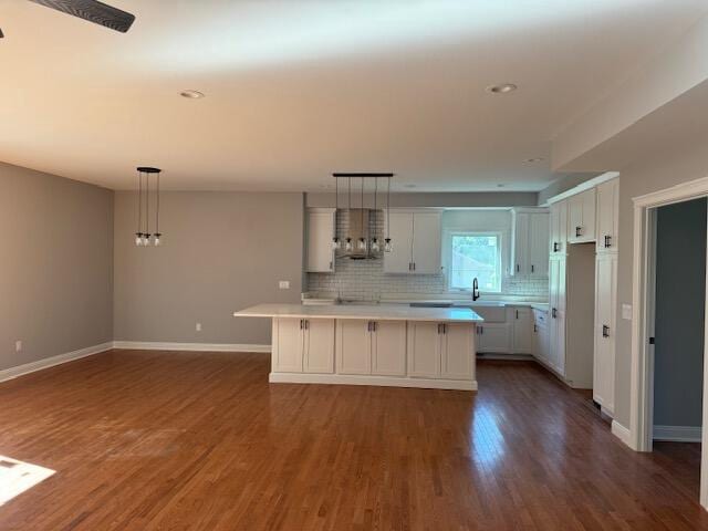 kitchen with hanging light fixtures, decorative backsplash, white cabinets, a center island, and dark hardwood / wood-style floors