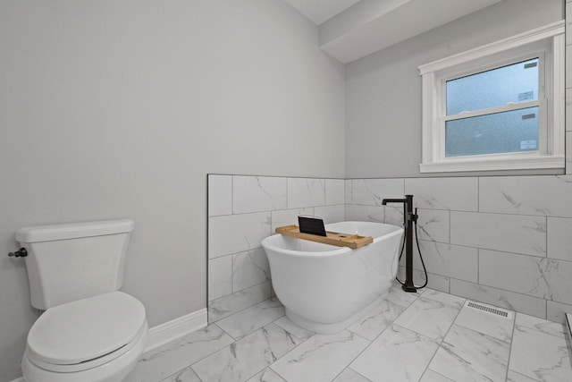 bathroom with tile walls, toilet, and a tub