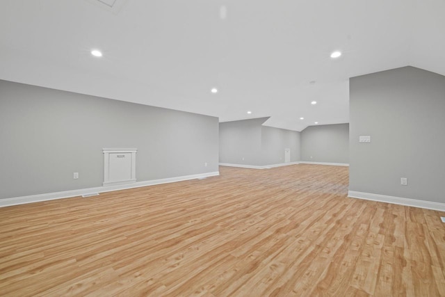 unfurnished room featuring light wood-type flooring and vaulted ceiling