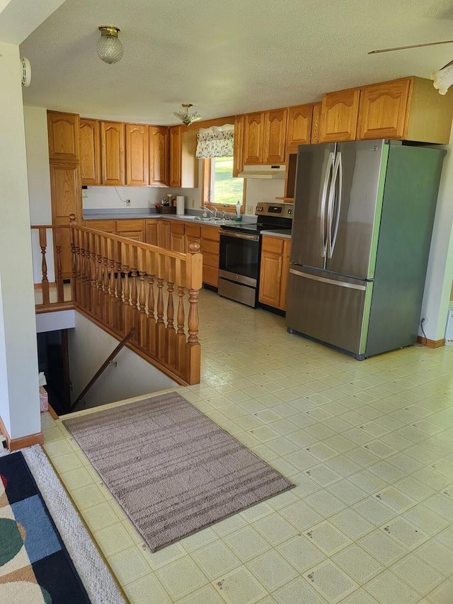 kitchen with a textured ceiling, stainless steel appliances, and sink