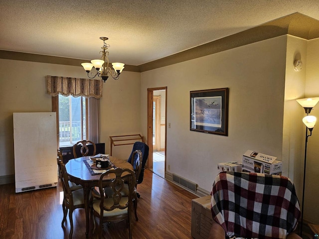 dining room featuring a textured ceiling, dark hardwood / wood-style floors, and an inviting chandelier