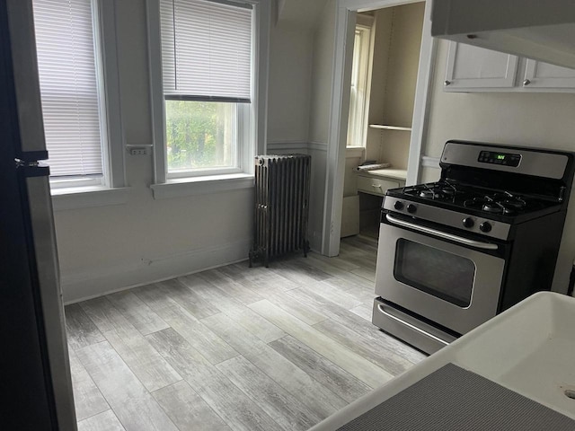 kitchen featuring light hardwood / wood-style flooring, radiator heating unit, and appliances with stainless steel finishes