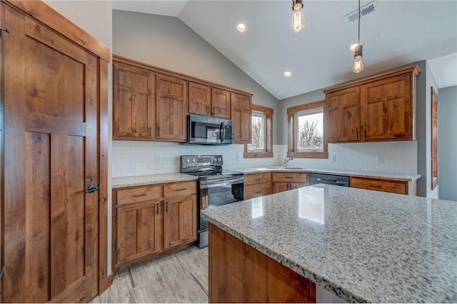 kitchen featuring tasteful backsplash, light stone countertops, appliances with stainless steel finishes, lofted ceiling, and light hardwood / wood-style floors