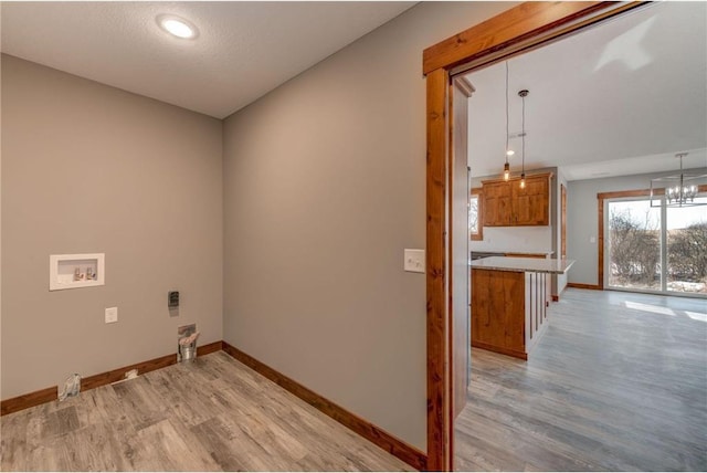 washroom with washer hookup, a chandelier, a textured ceiling, and light hardwood / wood-style flooring