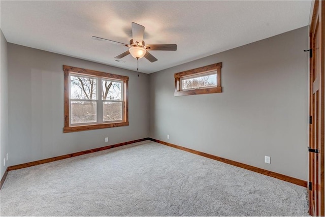 spare room featuring ceiling fan, light colored carpet, and a textured ceiling