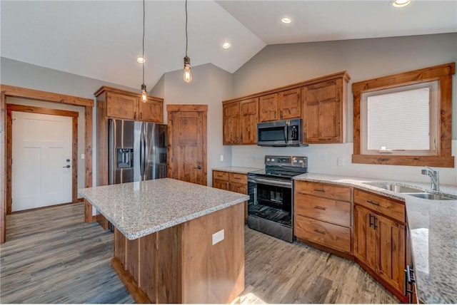 kitchen featuring a center island, vaulted ceiling, light stone counters, and stainless steel appliances