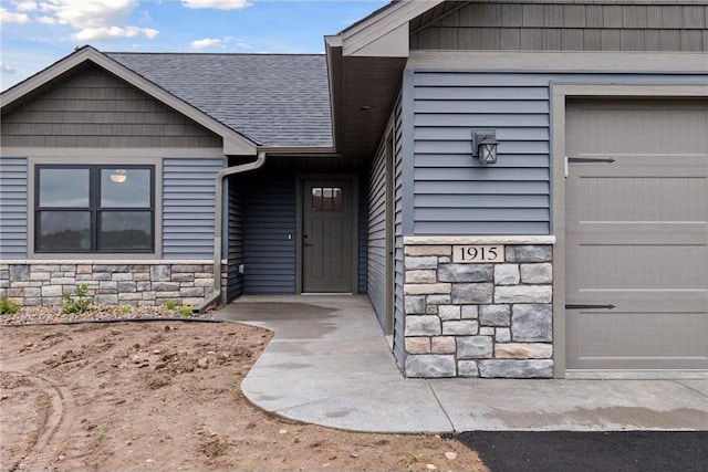 1915 Otter Way, New Richmond, WI 54017 - view of exterior entry featuring stone siding, a shingled roof, and a garage