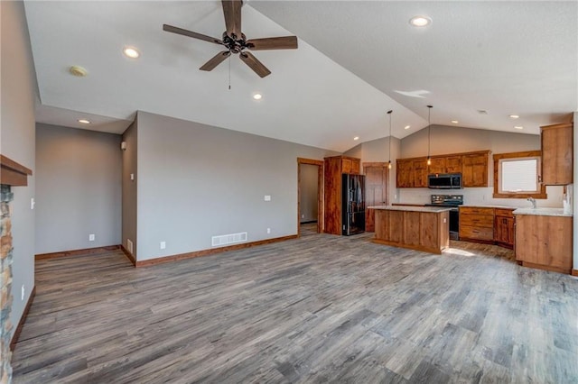 1915 Otter Way, New Richmond, WI 54017 - kitchen with stainless steel microwave, range with electric cooktop, black fridge, open floor plan, and vaulted ceiling