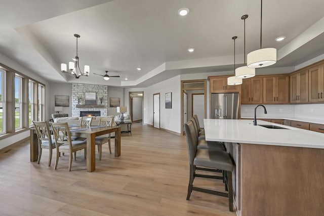 1629 N Honeysuckle Cir, De Pere, WI 54115 - dining space featuring light wood-style flooring, recessed lighting, a stone fireplace, ceiling fan with notable chandelier, and a tray ceiling