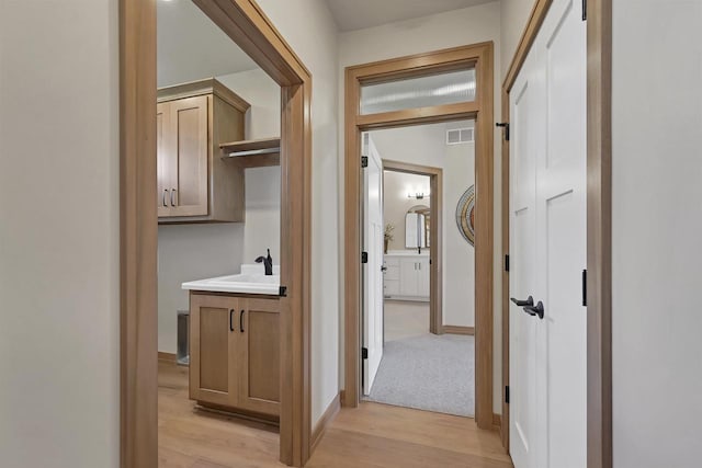 1629 N Honeysuckle Cir, De Pere, WI 54115 - hall featuring a sink, baseboards, visible vents, and light wood-type flooring