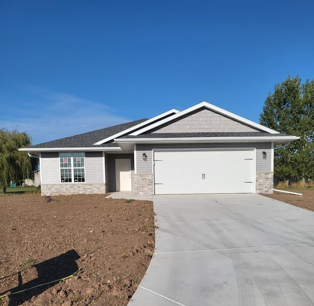 view of front facade featuring stone siding, concrete driveway, and a garage