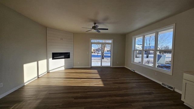 unfurnished living room with baseboards, a large fireplace, visible vents, and dark wood finished floors