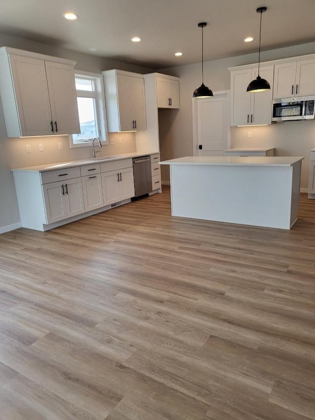 kitchen with light wood-type flooring, pendant lighting, recessed lighting, appliances with stainless steel finishes, and white cabinets