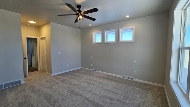 empty room with carpet, visible vents, and baseboards