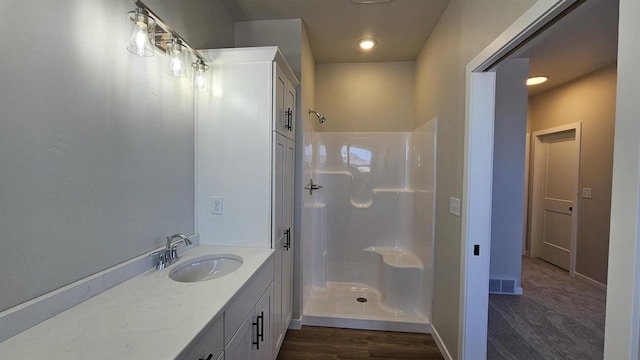 bathroom with baseboards, walk in shower, wood finished floors, and vanity