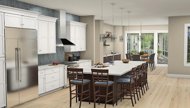 kitchen with a center island with sink, premium appliances, light hardwood / wood-style flooring, and decorative light fixtures