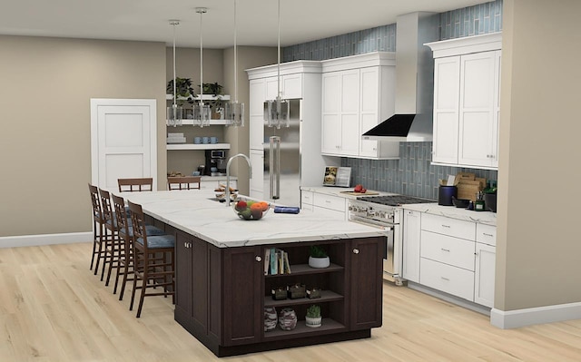 kitchen with an island with sink, high end appliances, light hardwood / wood-style floors, and hanging light fixtures