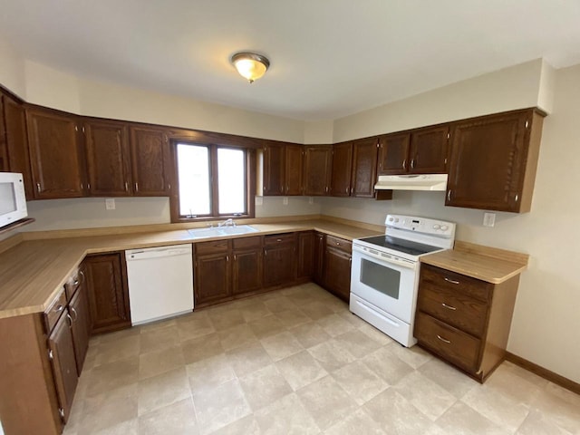 kitchen featuring white appliances, a sink, light countertops, dark brown cabinetry, and under cabinet range hood