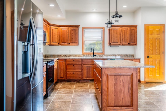 kitchen featuring a kitchen island, sink, light stone countertops, decorative light fixtures, and appliances with stainless steel finishes