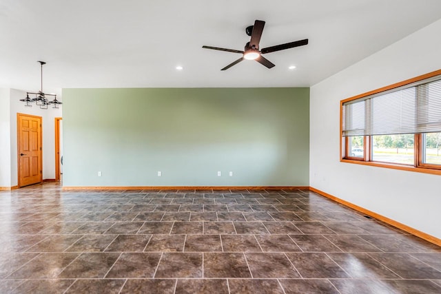 spare room featuring ceiling fan with notable chandelier