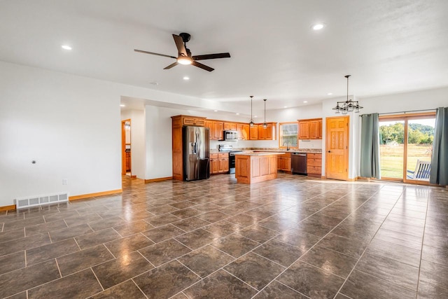 kitchen with a kitchen island, hanging light fixtures, stainless steel appliances, sink, and ceiling fan with notable chandelier