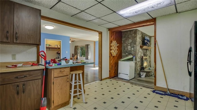 kitchen with a drop ceiling, light floors, a peninsula, and light countertops