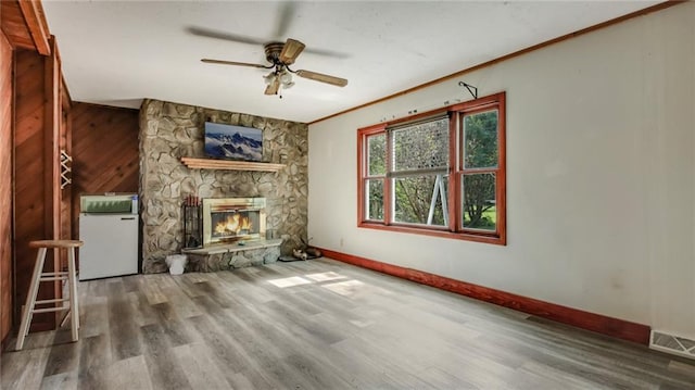 unfurnished living room featuring wood finished floors, visible vents, baseboards, a fireplace, and crown molding