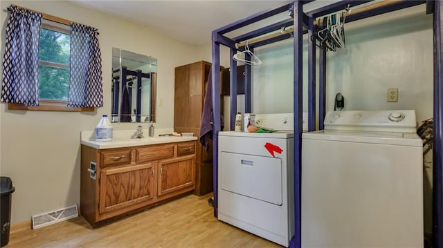 clothes washing area featuring visible vents, light wood-style floors, laundry area, and washer and clothes dryer